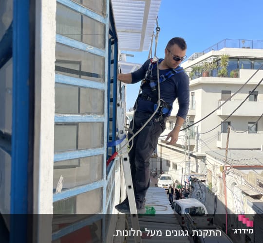 אדם על סולם ליד חלון אלומיניום בבניין